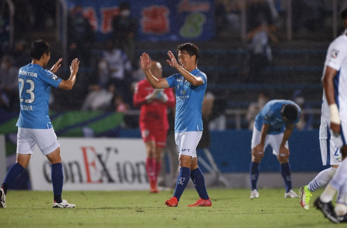 サッカーの試合後に選手とハイタッチをする岩武克弥