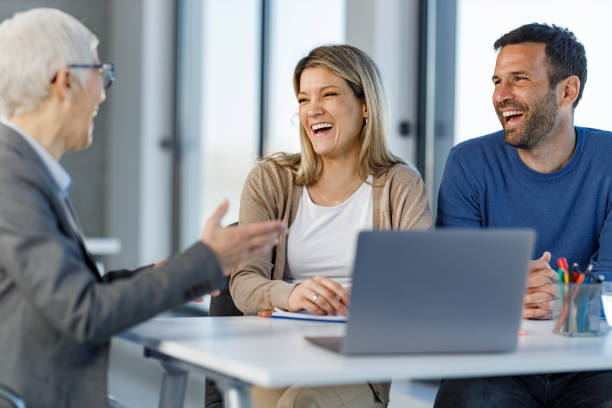 Happy couple having a conversation with their insurance agent during a meeting in the office.