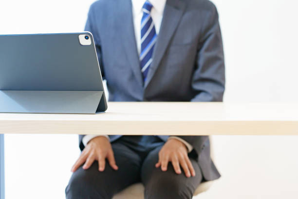 Asian man in a suit attending an online interview or meeting with a tense look