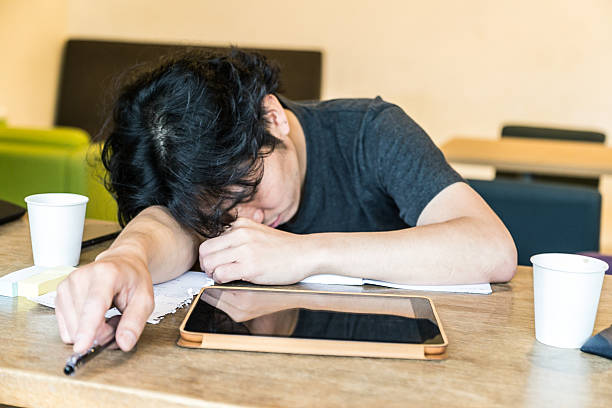 Japanese Student Fallen Asleep On His Textbook While Preparing For His Exams. In The Middle Of His Classroom.