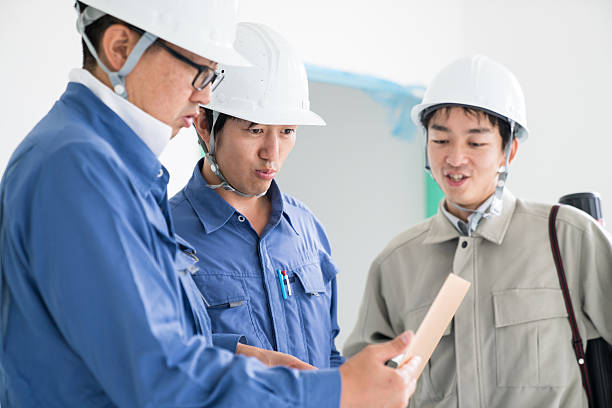 Team of engineers or architects at a building construction site looking at a laptop computer
