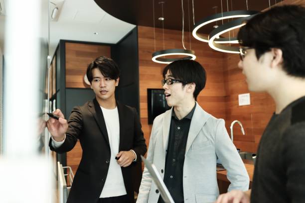 Three Asian entrepreneur males standing in front of a whiteboard together