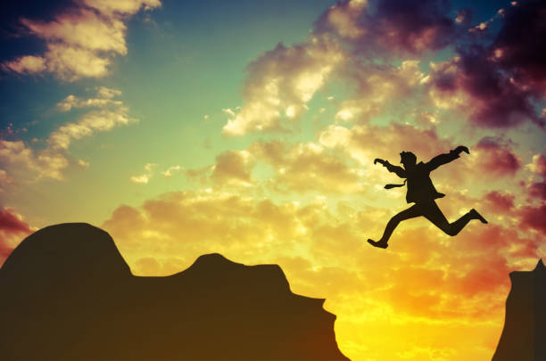 Businessman jumps over rocky mountain. Business and success concept